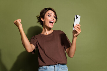 Photo portrait of lovely young lady hold device raise fist celebration dressed stylish brown...