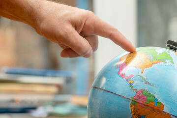 Close up of a male hand pointing at a globe in a classroom