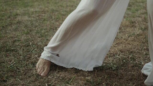 Ease in movement, beautiful female legs move smoothly. A young woman in wide trousers moves smoothly and beautifully, dancing alone. Morning qigong practice, oriental gymnastics.