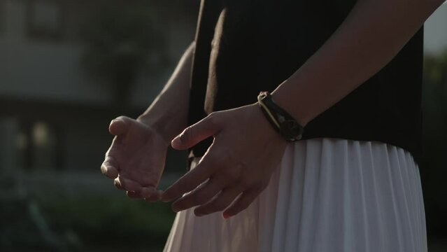 One european woman practicing qigong outdoors. Asian bracelet on a woman's hand. Body position control. Slow controlled calisthenics. Chinese philosophy. Tai-chi. Yin yang.