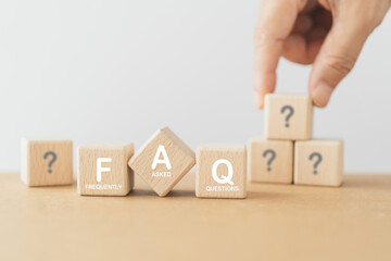 FAQ , Frequently asked questions concept, asked questions on any topic and answers.  White FAQ text on wooden cube block with blurred hand choose top question mark including copy space