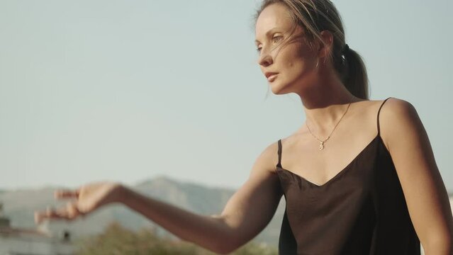 A woman is engaged in oriental practice in nature, the wind is in her hair. Balance, inner strength, meditation. Qigong instructor shows a set of exercises.
