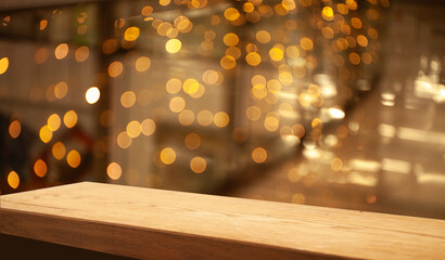 Empty wooden table top on blur light golden bokeh of cafe restaurant, bar in a dark background.