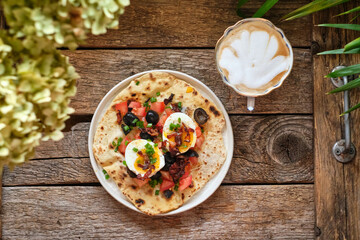 Flatbread with cboiled egg, tomatoes, fried bacon, green onions and olives. Wooden background, top view