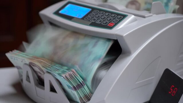 Counting machine for banknotes. Ukrainian money in a calculating machine. Ukrainian hryvnia is counted by a machine for banknotes. 