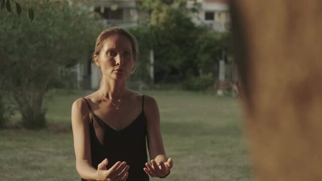 Female qigong master moves gracefully while doing movement and breathing practices in a city park. Harmony of body and spirit. Taoist traditional exercises. Tai ji, concentration, wushu, yin yang