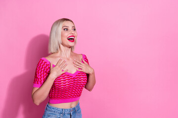 Portrait of astonished lovely girl hands touch chest look empty space ad isolated on pink color...