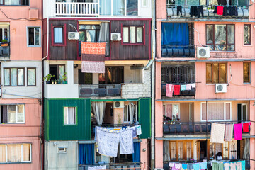 travel to Georgia - facade of multi-storey house in residential district in Batumi city with laundry drying on balcony on sunny morning