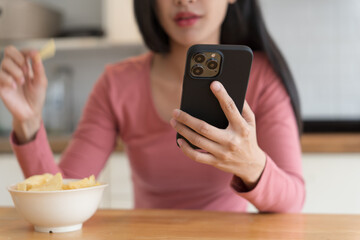 Asian woman eating while holding smartphone phone addiction concept