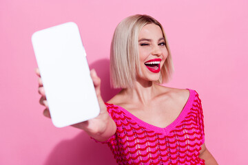 Photo of flirty girl with short hairdo dressed knitwear top recommend eshop on smartphone screen blinking eye isolated on pink background