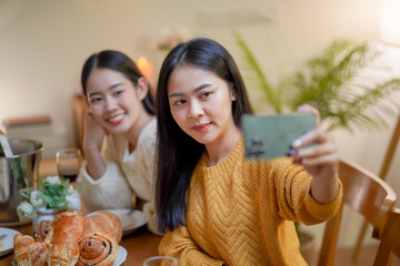 Obraz na płótnie Canvas Asian sister friends making selfie and smiling with smartphone. celebrating with Birthday cake.