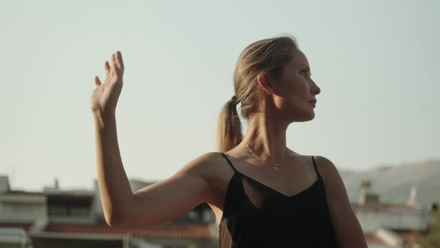 A young woman practices qigong at dawn alone, moving her arms smoothly. Spiritual practice in solitude. Psychopractice, a set of exercises. Health preservation system.