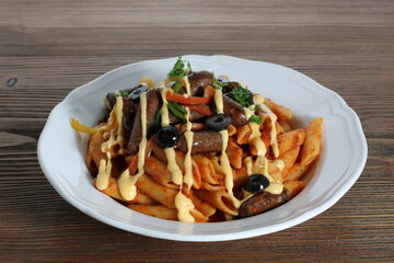Sausage pasta and cheese with black olive served in dish isolated on table top side view of arabic food