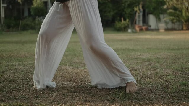 Ease in movement, beautiful female legs move smoothly. A young woman in wide trousers moves smoothly and beautifully, dancing alone. Morning qigong practice, oriental gymnastics.