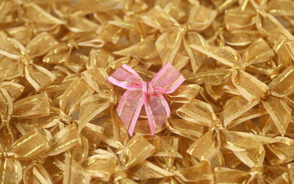 a gold bow ribbon on pink bows ribbon background