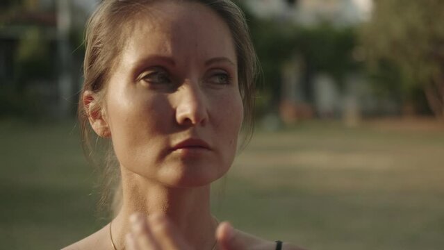 Portrait of a beautiful European woman with blond hair slowly turns. The woman's face, she in spiritual practices and oriental gymnastics. Female qigong instructor moves smoothly, moves her arms