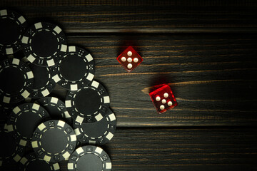 Popular poker dice or Craps game on a dark vintage table and chips from a lucky win. Space for advertising - obrazy, fototapety, plakaty