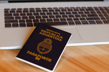 Passport of the Argentine Republic and Mercosur on a notebook keyboard and a wooden table to obtain air tickets.