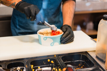 Unrecognizable man chef preparing healthy and delicious poke dish in kitchen