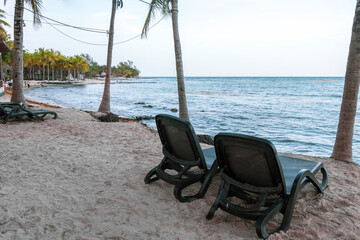 Palapa thatched roofs palms parasols sun loungers beach resort Mexico.