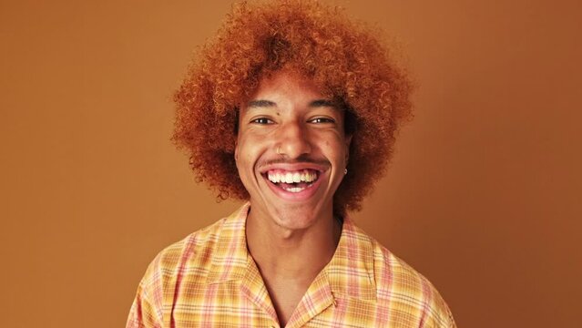 Guy is emotionally telling something and looking at camera isolated on brown background in studio