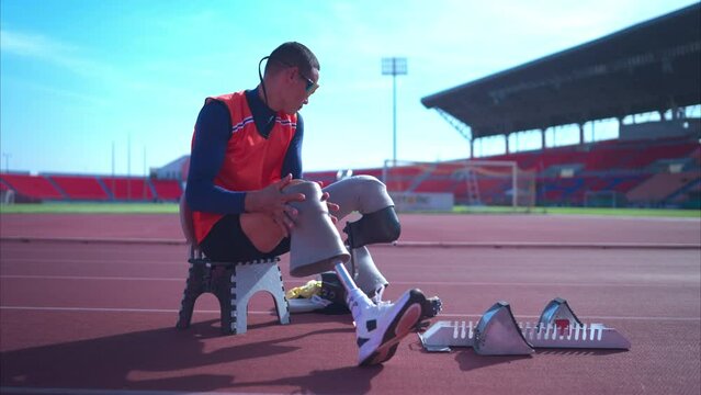 Disabled athletes prepare the blade running in starting position ready to run on stadium track