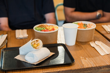 Anonymous friends sitting in restaurant at table with delicious food