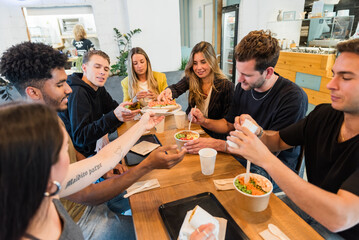 Diverse friends eating food in cafeteria together