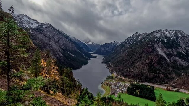 Aerial drone view time lapse Plansee lake among snow-capped mountains in Tyrolean Alps, Austria late autumn in cloudy weather. High quality 4k footage