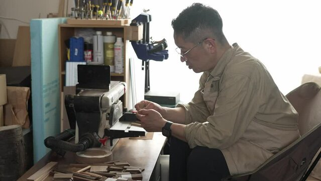 室内の作業場でヤスリがけをする職人の横姿