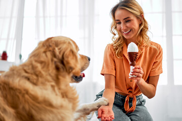 Training with fun. Obedient golden retriever giving paw to female owner while spending time...