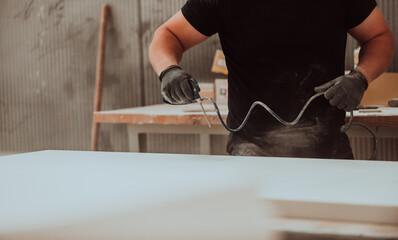 A dedicated worker in the woodworking industry employs compressed air to meticulously clean wooden...