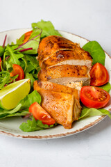 Salad with chicken breast, fillet with lettuce and cherry tomatoes on a plate on a light background, close up