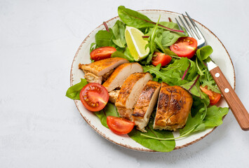 Salad with chicken breast, fillet with lettuce and cherry tomatoes on a plate on a light background, horizontal, free space for copying..