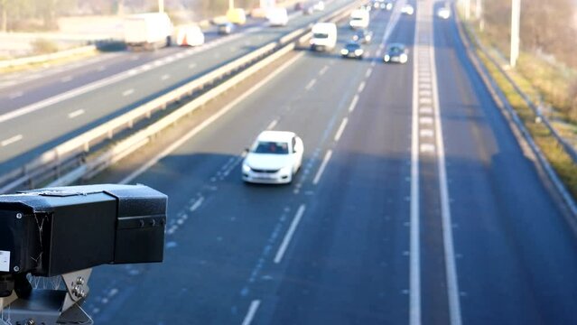 Close up of black security or speed camera watching highway, motorway traffic on frosty winter day.