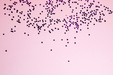 Christmas greeting background with empty space. Violet sparkle sequins, glitter on a light pink background. Top view