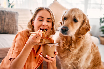 Portrait of a beautiful woman sitting and enjoying with closed eyes a delivery noodle and her dog...