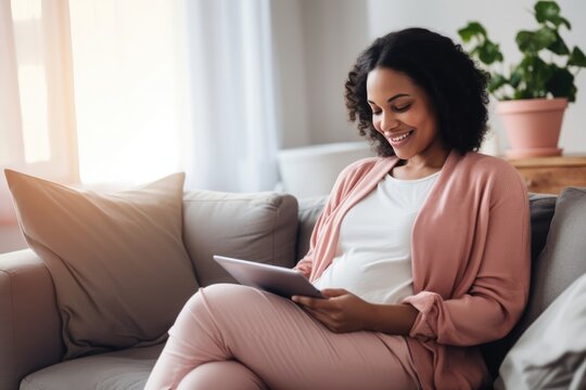 Photo of a pregnant woman reading online news on a laptop in her living room 