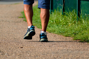 Man walking with sneakers on a path, close-up of his legs, sports activity, healthy lifetsyle