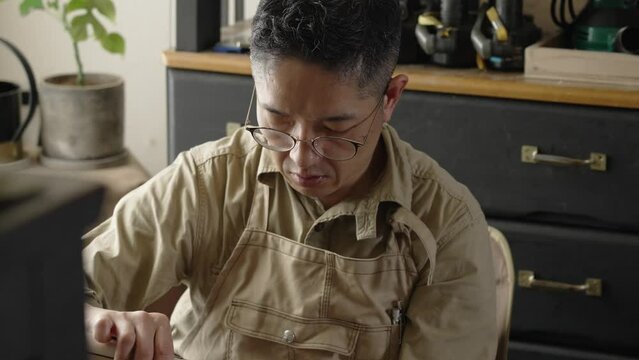 手作業をする木工作家のバストショットから手元へのチルトダウン