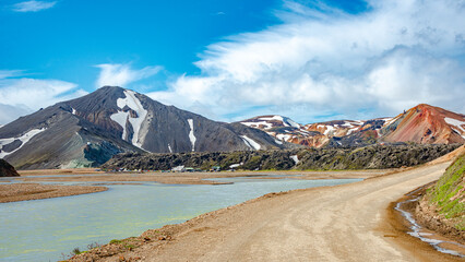 Landmannalaugar, Iceland, Gravel road near water stream at camping and mountain hut, Icelandic landscape of colorful rainbow volcanic mountains at Laugavegur hiking trail