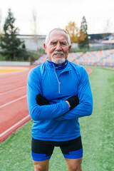 Energetic senior Caucasian man in blue sports gear enjoys a running session on a clear day.