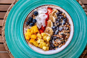 a close up view over a bowl of freshly prepared ice cream topped with sliced fruits and oats