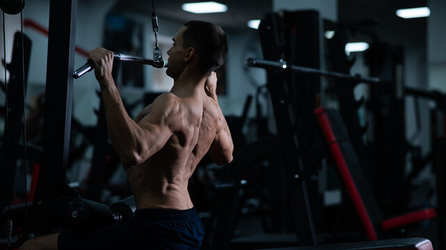 A man does a chest pulldown in the gym.