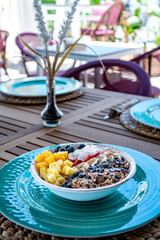 a portrait image of a bowl of acai ice cream topped with fresh fruits at a mediterranean restaurant