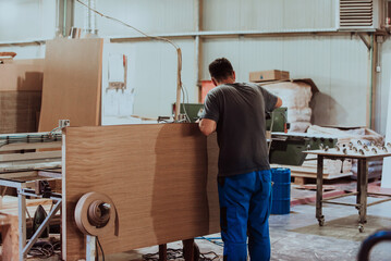 A skilled worker in the woodworking industry adeptly utilizes modern machinery to process and prepare wooden doors for the market, showcasing a seamless blend of traditional craftsmanship and cutting