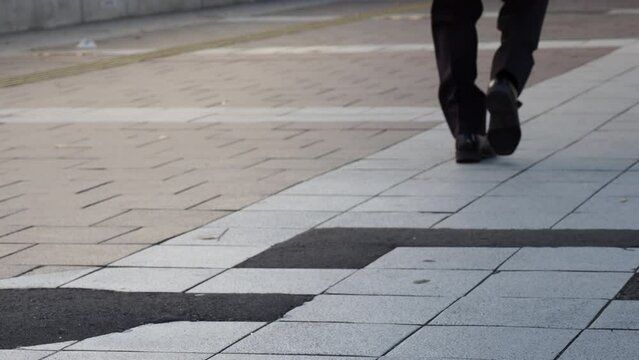 オフィス街の路面を通行している男性サラリーマンの足の様子