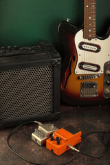 Vintage electric guitar, guitar amplifier and effects pedals for the guitarist against a dark green...