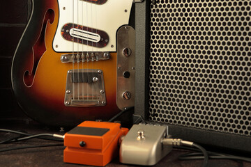 Vintage electric guitar, guitar amplifier and effects pedals for the guitarist on a dark brick...