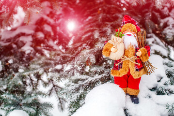 Santa Claus stands on the background of a snow-covered spruce
